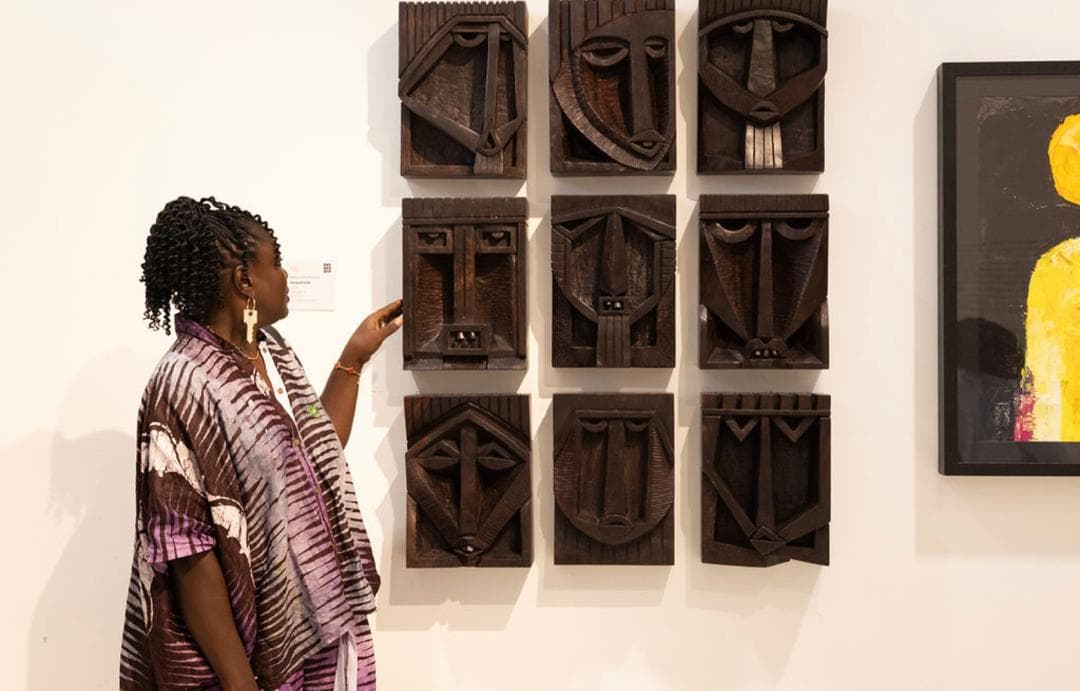 A visitor reading the grid of carved faces, panel by panel.
