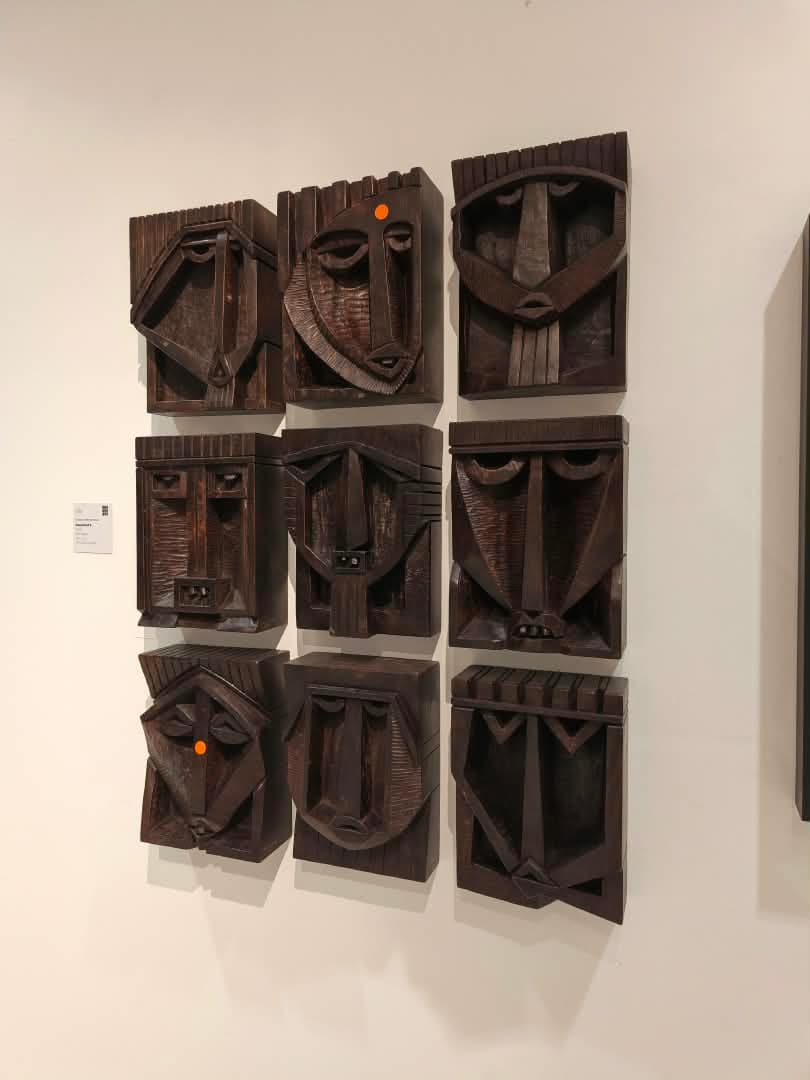 Nine carved heads, hung as one piece.